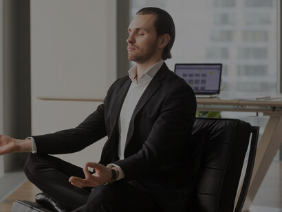 In a modern office, a smiling businessman engages in relaxation techniques, including mindfulness and breathing exercises, to effectively manage anxiety and boost his mental well-being