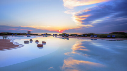 The sunset from the Hotel Torreruja terrace paints the sea in golden hues, offering a serene escape, Over Isola Rossa, Sardinia, Italy