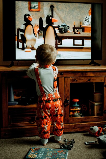 Bimbo in piedi davanti alla televisione: “anche i programmi educativi tendono a utilizzare colori vivaci e cambi rapidi di scena, che possono sovrastimolare il cervello del bambino”