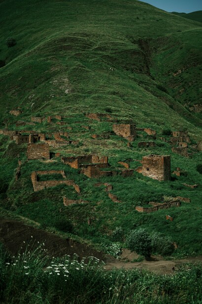 Ancient stone ruins scattered across the green hills of Chechnya, Russia, representing the passage of time and the new reality of a region once known mainly through images of war