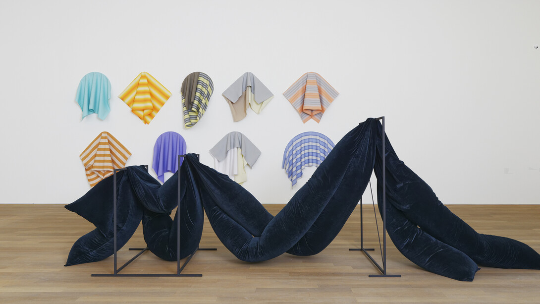 Vue de l’exposition Flatland / Abstractions narratives #2, 07.10.2017 - 15.04.2018,
Mudam Luxembourg
Avant-plan :
Laëtitia Badaut Haussmann
l'Amour est plus froid que la mort, 2015
Acier et aluminium, velours, mousse
237 x 450 x 144 cm
Courtesy de l’artiste et Galerie Allen, Paris
Arrière-plan :
Sonia Kacem
Sans titre (orange, feu), 2016
Sans titre (violet), 2016
Sans titre (turquoise), 2016
Sans titre (rose et gris), 2016
Sans titre (blanc), 2016
Sans titre (coquillage), 2016
Sans titre (mocca), 2016
Sans titre (bleu), 2016
Sans titre (beige), 2016
Tissu de marquise, bois
Dimensions variées
Courtesy de l’artiste et Galerie Gregor Staiger, Zurich
© Photo : Aurélien Mole / Mudam Luxembourg