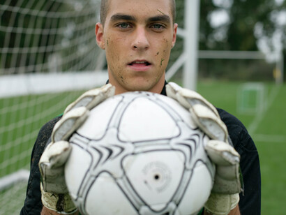 Goleiro agarra a bola do time adversário em campo e mostra para a câmera 