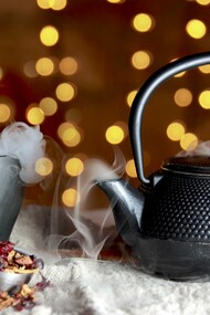 Chaleira e xícara exalam vapor de chá de menta com infusão de morangos