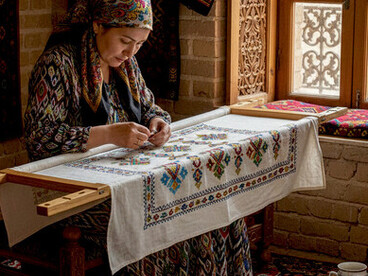 An Uzbek master craftswoman meticulously works on a suzani-style tablecloth, preserving the ancient art of hand embroidery