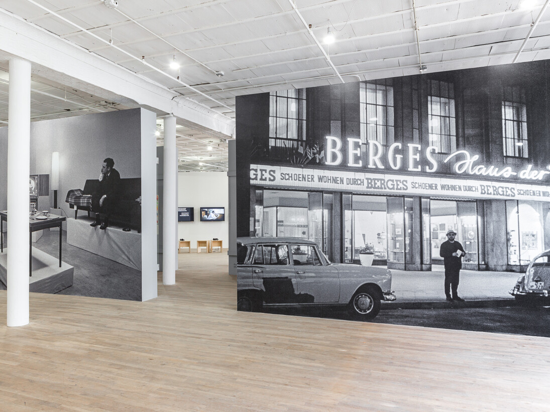 Installation view from Living with Pop. A Reproduction of Capitalist Realism, Artists Space, 2014. Left: Leben mit Pop - Eine Demonstration für den kapitalistischen Realismus, 1963 (Living with Pop – A Demonstration for Capitalist Realism) © 2014 Artists Rights Society (ARS), New York / VG Bild-Kunst, Bonn. Photo: Reiner Ruthenbeck. Inkjet print on vinyl mounted to wall Right: Exterior view of the furniture store Möbelhaus Berges Flingerstraße 11, Düsseldorf. Courtesy Archiv künstlerischer Fotografie der rheinischen Kunstszene (AFORK) © 2014 Artists Rights Society (ARS), New York / VG Bild-Kunst, Bonn. Photo: Reiner Ruthenbeck. Inkjet print on vinyl mounted to wall