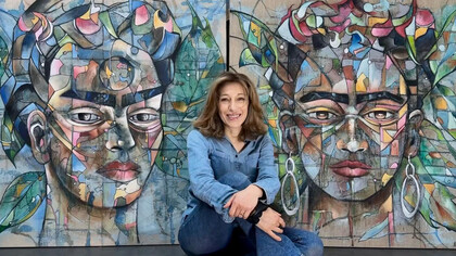 Frédérique Assaël frente a dos de sus retratos de Frida Kahlo