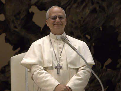 Papa Leão XIV durante uma audiência com a mídia, 2025. O cardeal Robert Francis Prevost, agora Papa Leão XIV, escolheu um nome carregado de significados históricos. O último Papa com esse nome, Leão XIII (1878–1903), foi inovador em seu tempo e procurou conciliar a tradição da Igreja com a dura realidade vivida pelos fiéis. Foi o grande articulador da Doutrina Social da Igreja. Em sua Encíclica Rerum Novarum (1891), defendeu a dignidade do trabalho, a Justiça Social e os direitos dos trabalhadores baseados na justiça e na equidade



