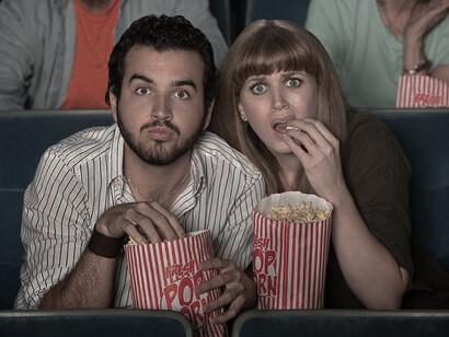 Dos jóvenes comiendo palomitas en el cine