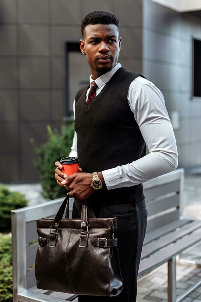 A man dressed in business casual clothing is holding a cup of coffe