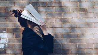 Mulher com livro no rosto. Somos contadores de histórias na nossa própria mente em forma de monólogo