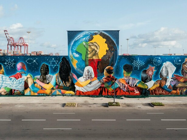 "Coexistence", de Eduardo Kobra, em Cotonou, na República do Benim em 2023. O mural reúne 12 figuras de costas, representando diferentes religiões, unidas diante de um globo que destaca a África e duas mãos entrelaçadas. Realizada na fachada do antigo Hotel do Porto, a obra ocupa cerca de 700 m² e transforma o espaço urbano em uma mensagem visual de tolerância, diálogo inter-religioso e convivência, reafirmando a presença internacional da arte urbana brasileira