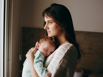 A woman holding her baby by the window