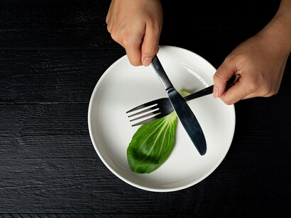 A woman makes a face as she avoids eating vegetables, choosing to eat other dishes instead