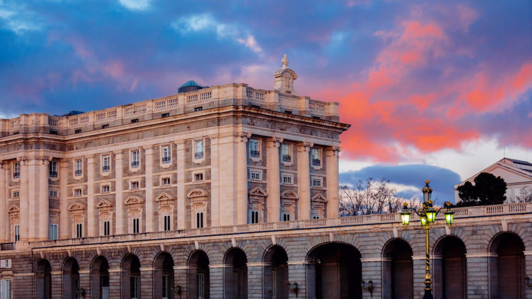Pink hues bathe the Royal Palace of Madrid at dusk, symbolising both the enduring legacy of Spanish royalty and the dynamic cultural exchange reshaping the city's social fabric