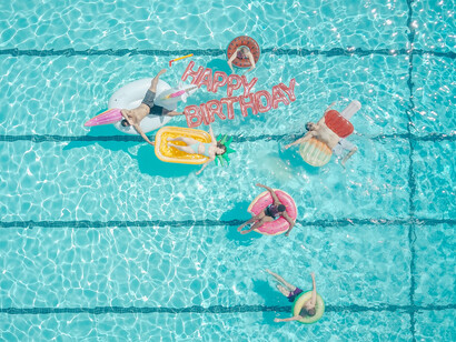 Six friends on their swimming pool floaties for a Happy Birthday pool party