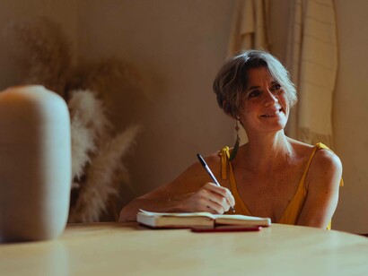 A woman happily thinks about and writes on things she would like to be doing