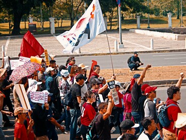 Citizens marching through the streets with banners demanding accountability, representing the belief that public pressure remains essential to democratic reform