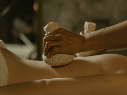 Hands applying warm herbal compresses to a person’s back—a classic Panchakarma therapy used in Ayurvedic healing