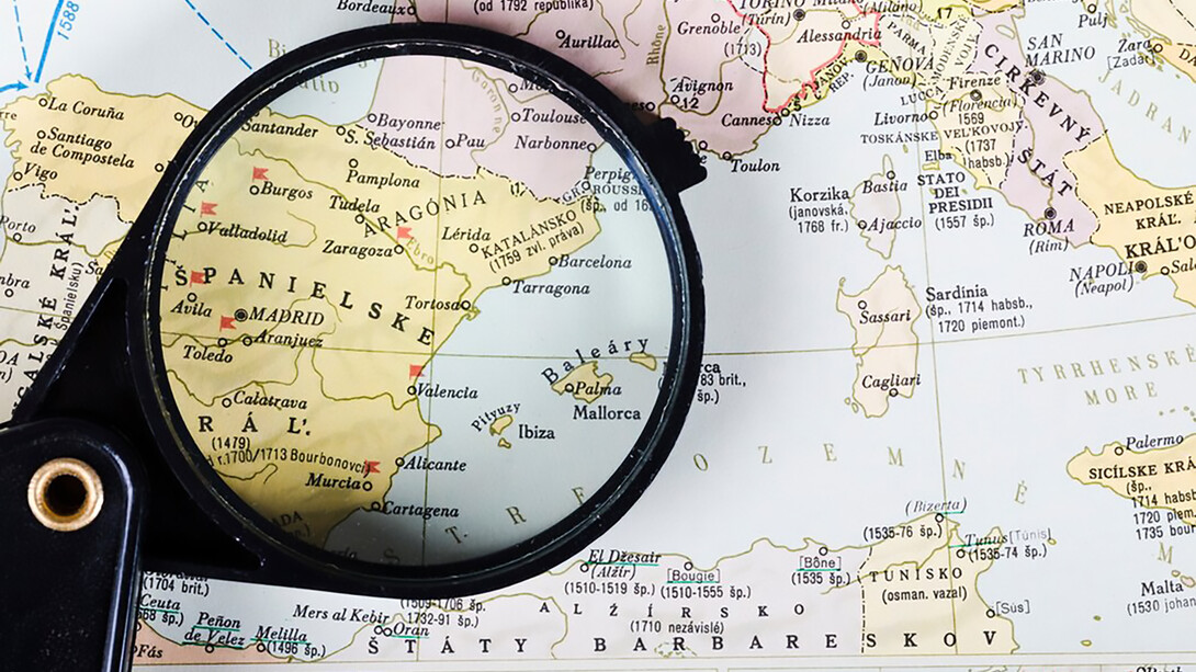 A magnifying glass revealing a map of Spanish cities