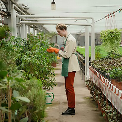 Man tending to his plants in a greenhouse, illustrating the connection between farming practices and climate change