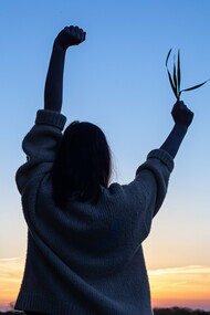 With arms raised in freedom and a sprig of life in hand, she embodies the power of simple, intentional choices to move, eat, and thrive toward a vibrant and healthy future