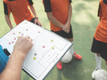 Coach instructing players on football tactics during training session