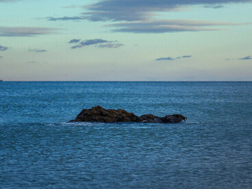 A solitary rock rising from the waters of Fnideq Beach, Morocco, representing resilience shaped by time and the sea