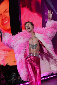 O cantor norte-americano Harry Styles em seu show nos Estados Unidos vestindo peças de paetê e casaco rosa