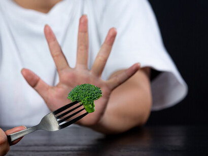 A woman displeased as she turns down vegetables on her meal, preferring other food options