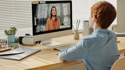 A young boy engaged in online learning, with his teacher conducting a virtual lecture through the screen