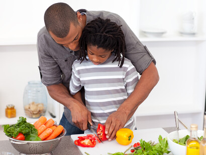 Daughter and father cut vegetables in the kitchen