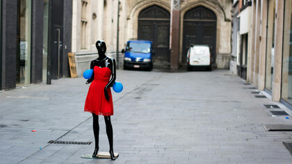 Black mannequin in a red dress displayed on the street