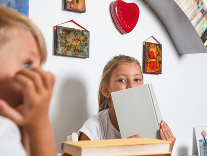 A boy and a girl sitting at a table, deeply engaged in reading and developing self-discipline through focused study