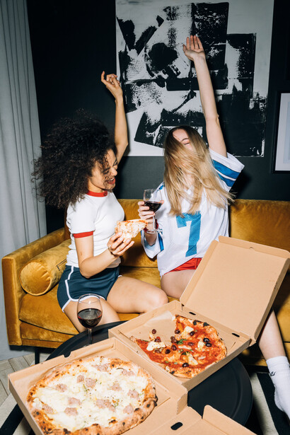 Amiga pedem pizza e bebem vinho no Airbnb no novo país que estão visitando de férias