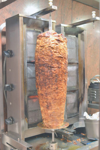 A doner kebab spit in a bustling fast food eatery, representing the essence of German street food