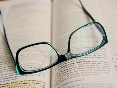 Glasses on an open textbook as a sign one is done for the day in terms of learning about language