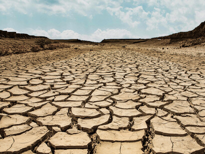 Parched, cracked earth lies beneath a partly cloudy sky, highlighting the tension between dryness and an uncertain atmosphere