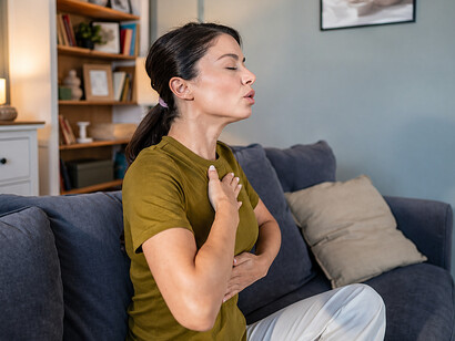 A woman practicing deep-breathing meditation at home, reflecting the connection between the mind, body, and emotional healing