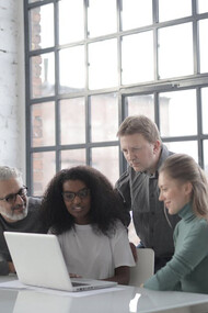 Sports managers collaborate around a computer, strategizing the future of sport management in an ever-evolving industry