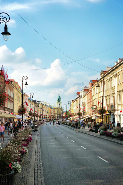 People crossing the street between modern concrete structures in Warsaw, Poland, reflecting the city's blend of urban design and daily life