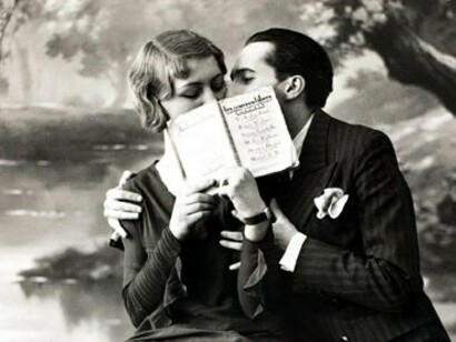 Una pareja se besa detrás de un libro