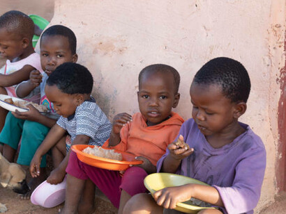Children in an African village eating together, a poignant reminder of the ongoing challenges of famine and malnutrition