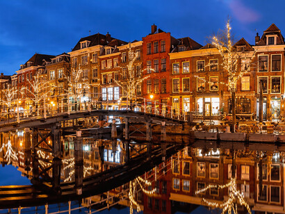 Warm Christmas lights reflect beautifully on a canal in Leiden, Netherlands
