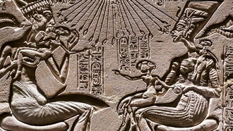 Akhenaten and Nefertiti seated, holding three of their daughters, under the rays of the sun god Aton