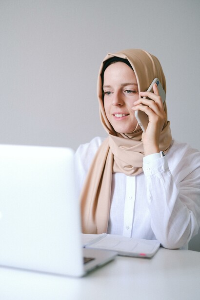 Woman talking on the phone and looking at her laptop