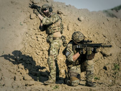 Two men in army uniforms with guns 