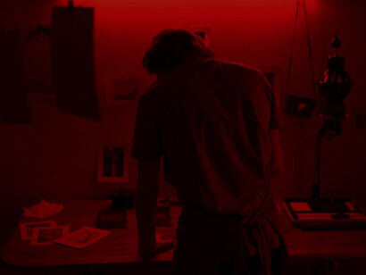 The artistry of photography as a man carefully develops photos in a vivid red room, showcasing creativity and precision in capturing memorable moments