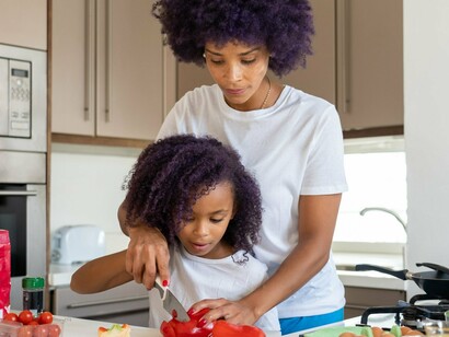 A mother teaching her child to prepare fresh ingredients, symbolising the preservation of family traditions through everyday moments