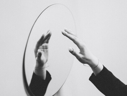 Una mano se acerca lentamente con cautela a su reflejo