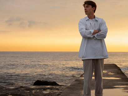 A thoughtful person gazes at the horizon by the ocean, finding peace and stillness in the tranquil beauty of nature